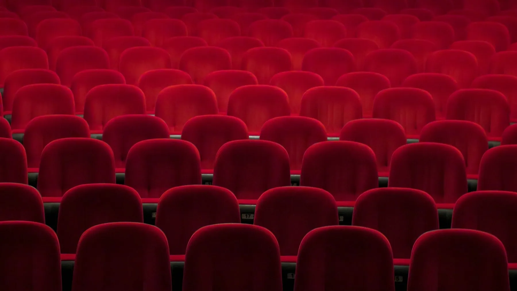 Empty red cinema seats lit in deep crimson