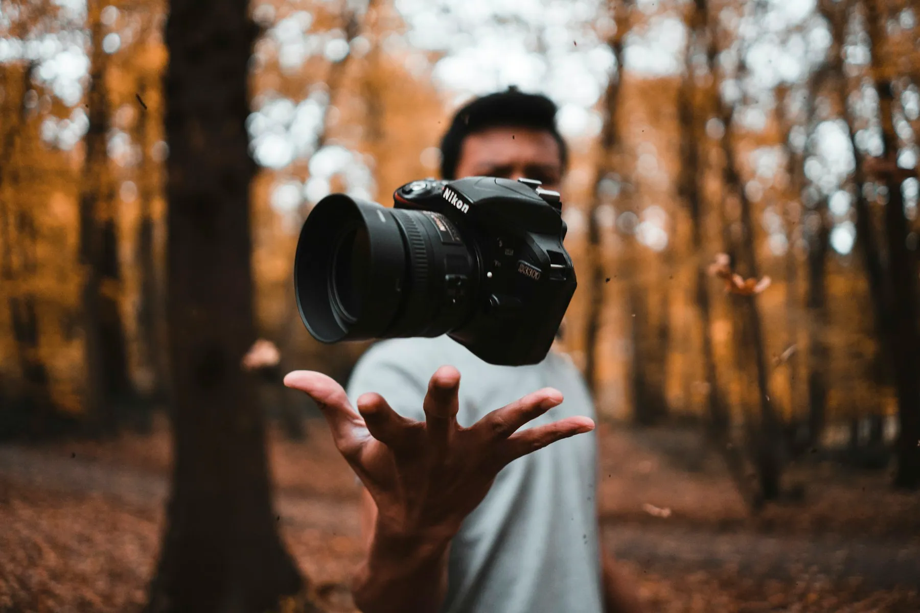 A photographer holding a camera lens in autumn light
