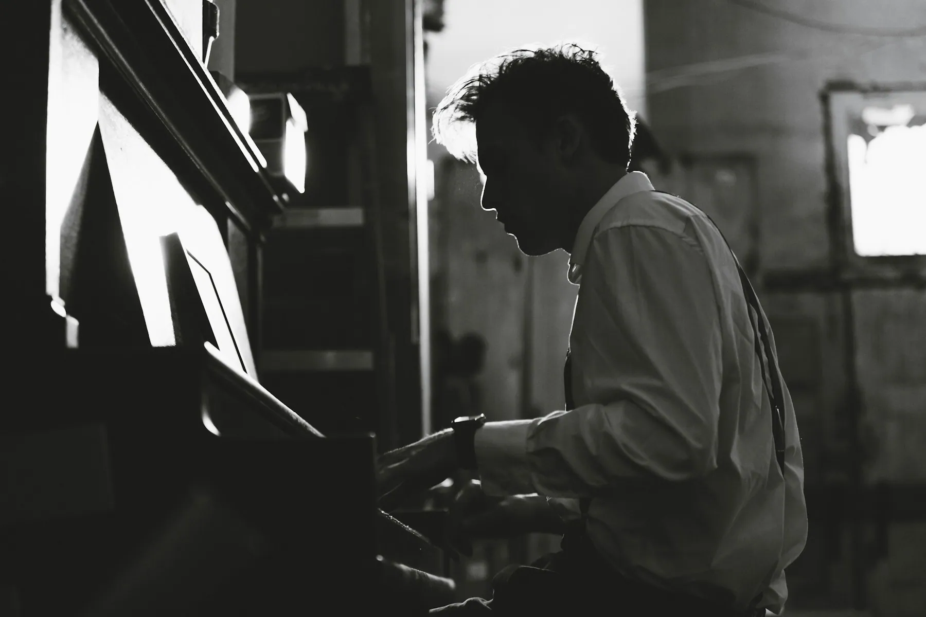 A musician playing piano in low, moody light